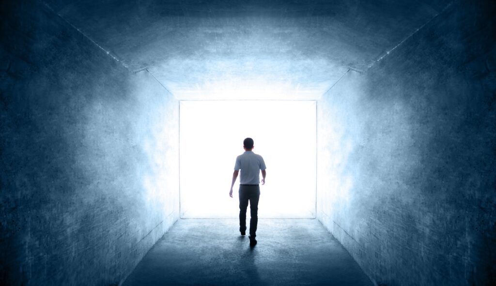 rear view of single young man walking through a dark tunnel