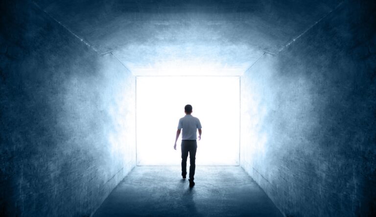 rear view of single young man walking through a dark tunnel