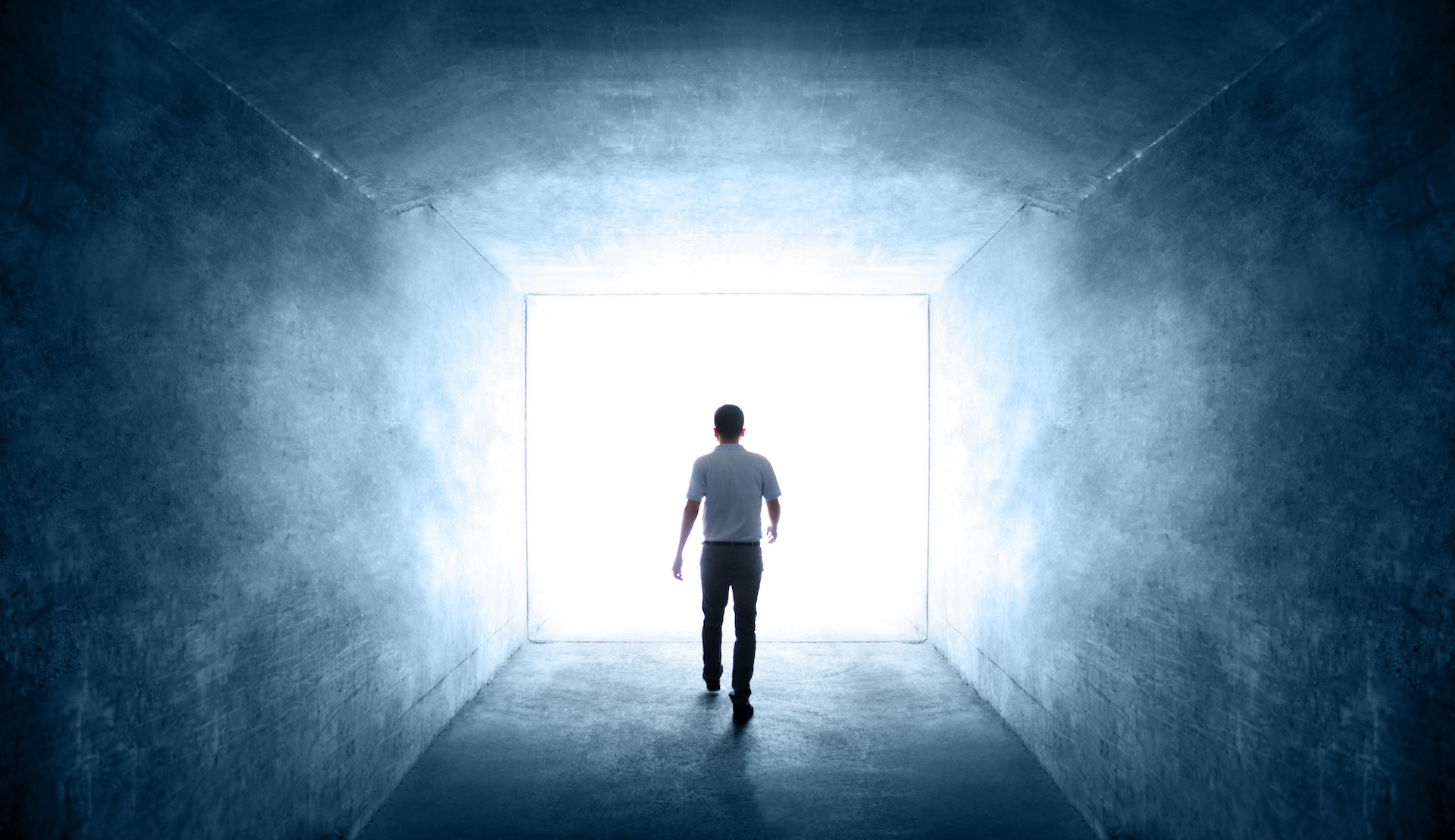 rear view of single young man walking through a dark tunnel